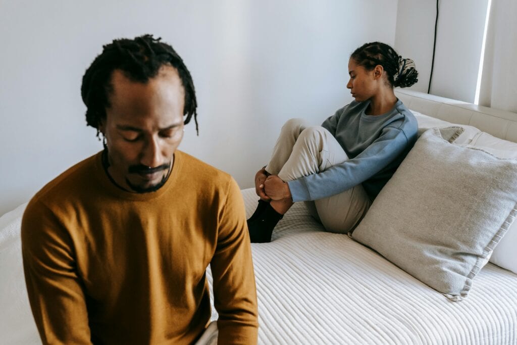 couple on bed looking away from each other sad
