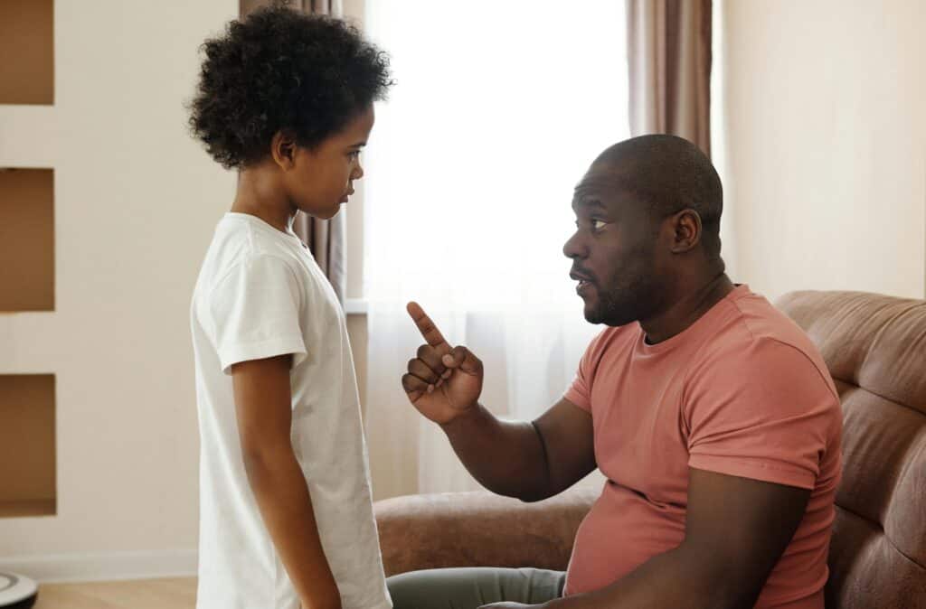 Dad sitting talking to preteen son with finger pointed