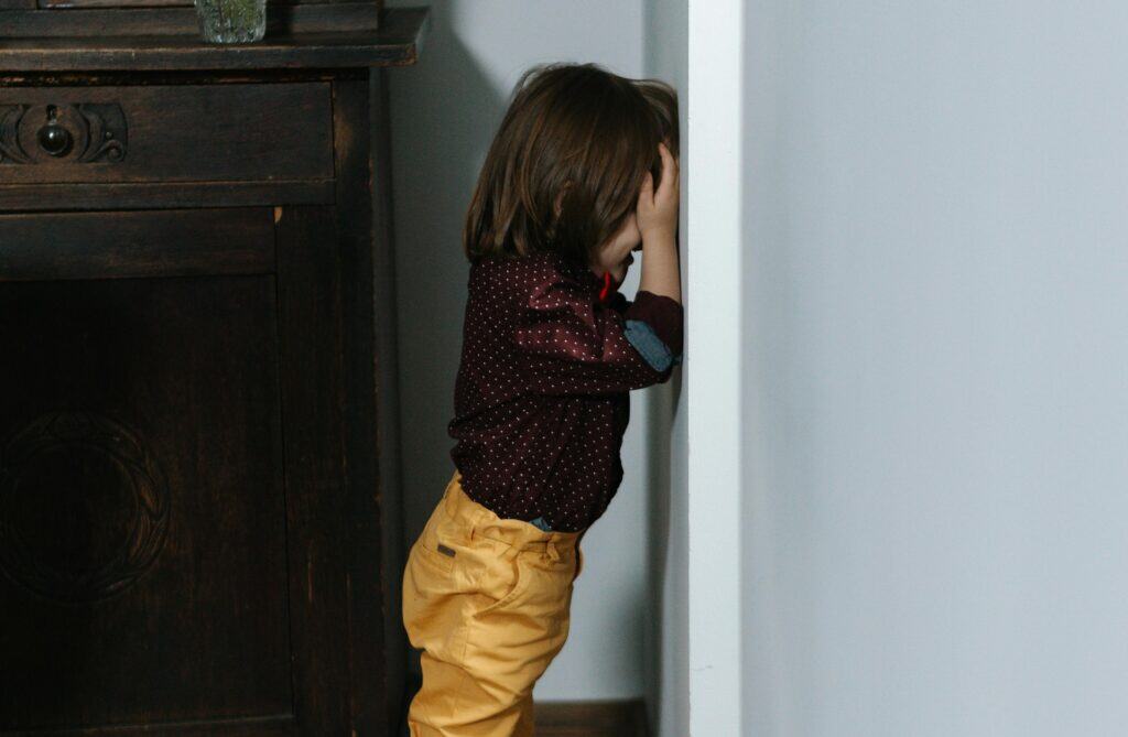 child standing up against the wall time out crying