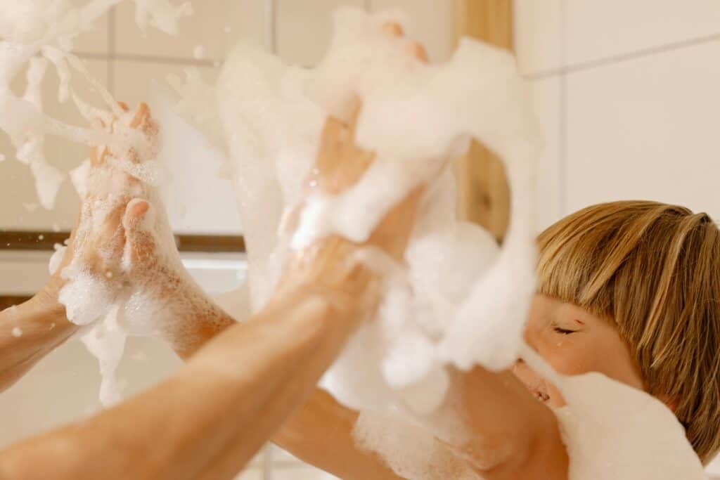 Baby and parent playing with bubble bath bubbles