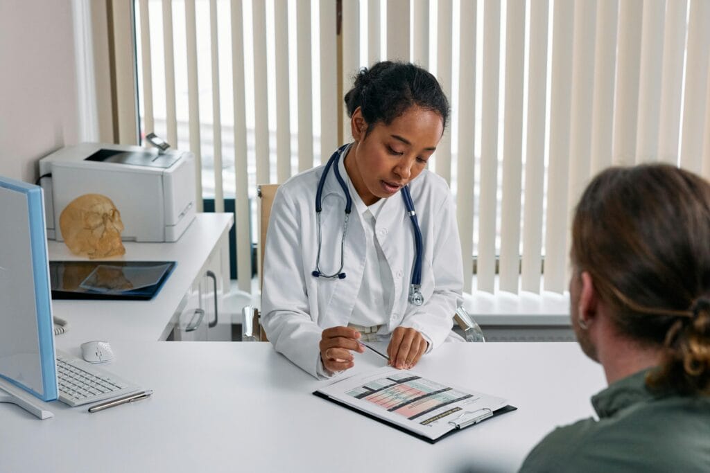 female doctor looking at chart male patient across desk
