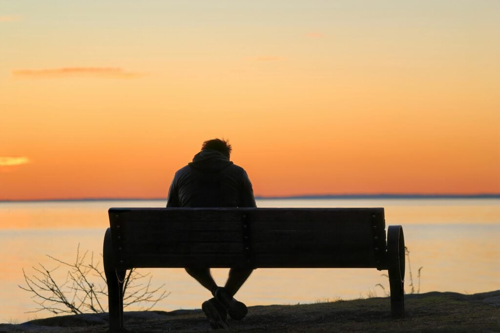 man on bench sunset head bowed