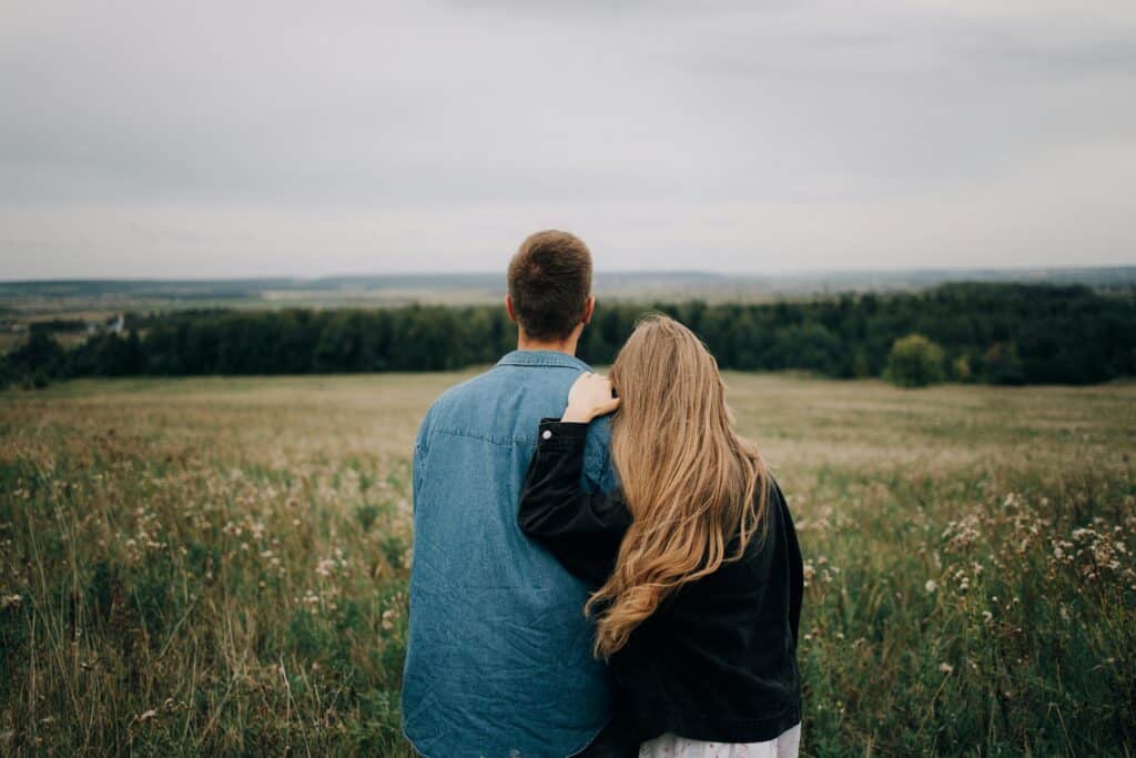 couple looking out over field and mountains backs