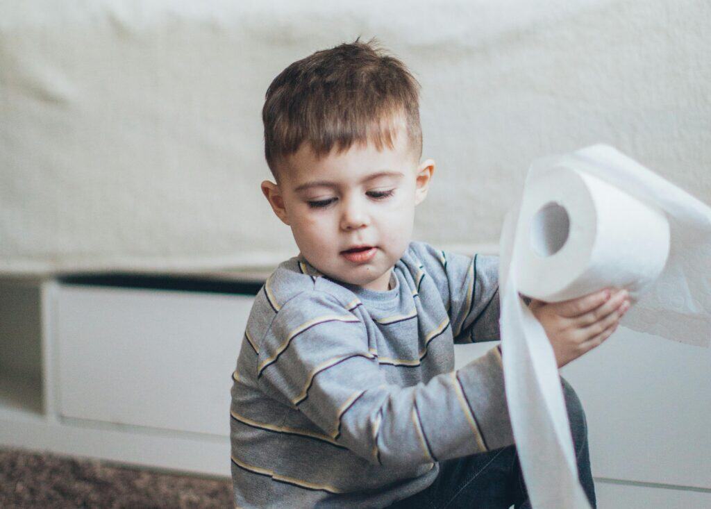 little boy playing with toilet paper roll