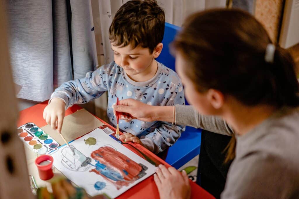 mom helping preschool boy paint pajamas
