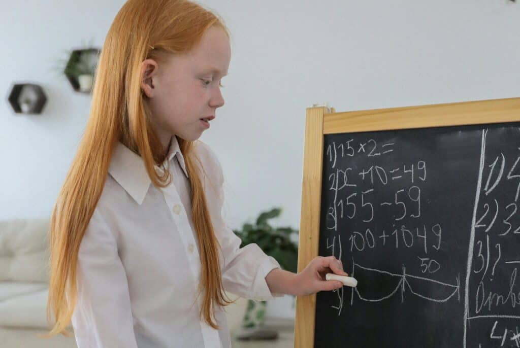 girl writing math on chalkboard