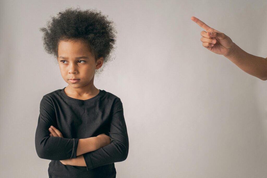 Child angry while adult finger points at her