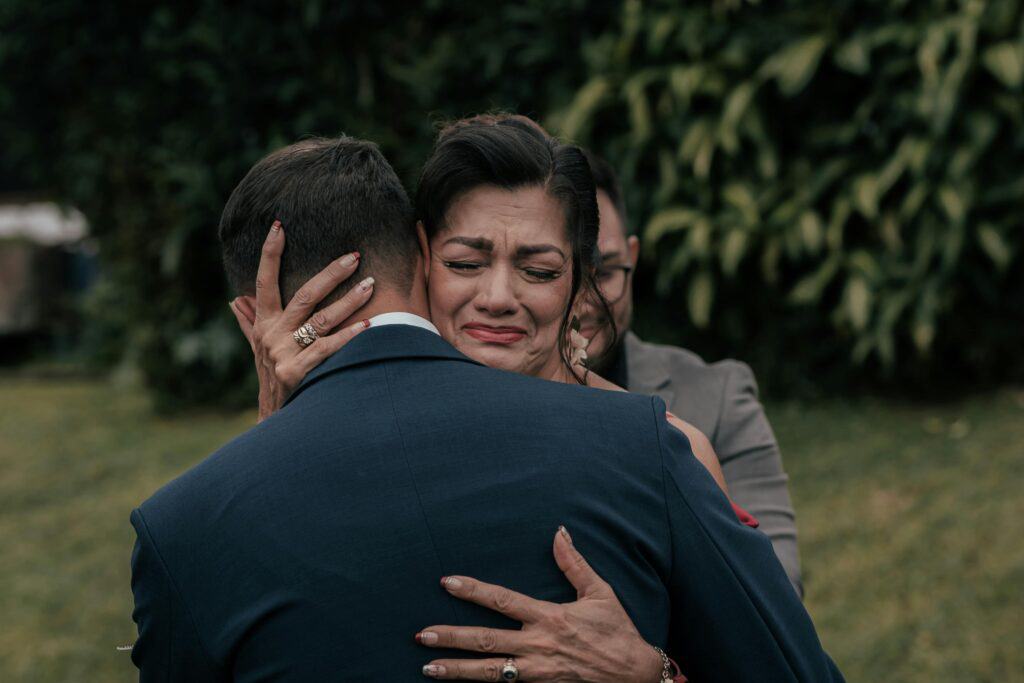 Mom hugging adult son who is wearing suit wedding