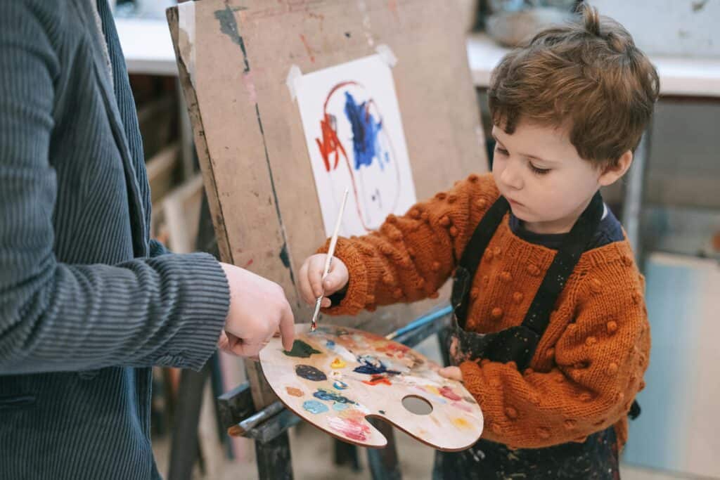 boy with teacher painting with easel