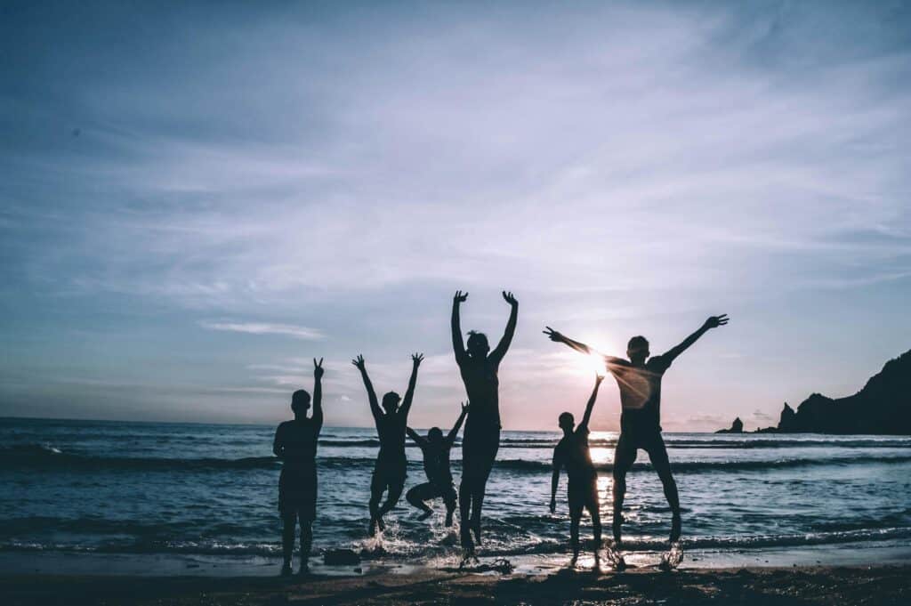 friends dancing on beach at sunrise