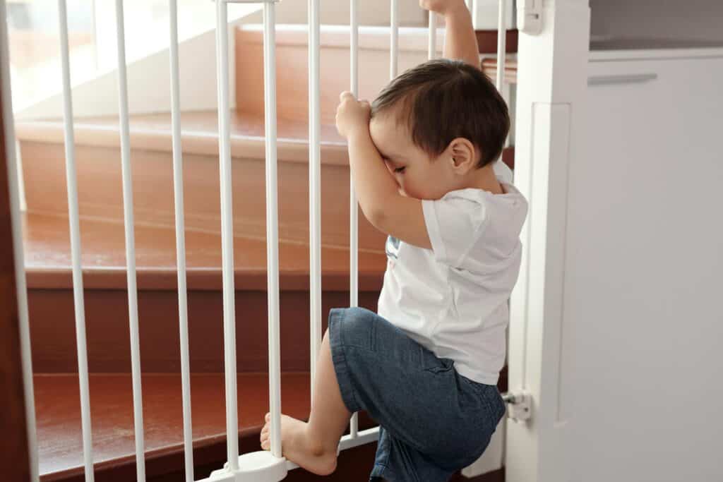 toddler climbing on baby gate