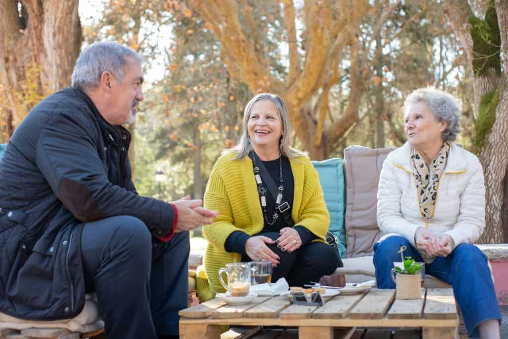 Older man and women talking ourside around table