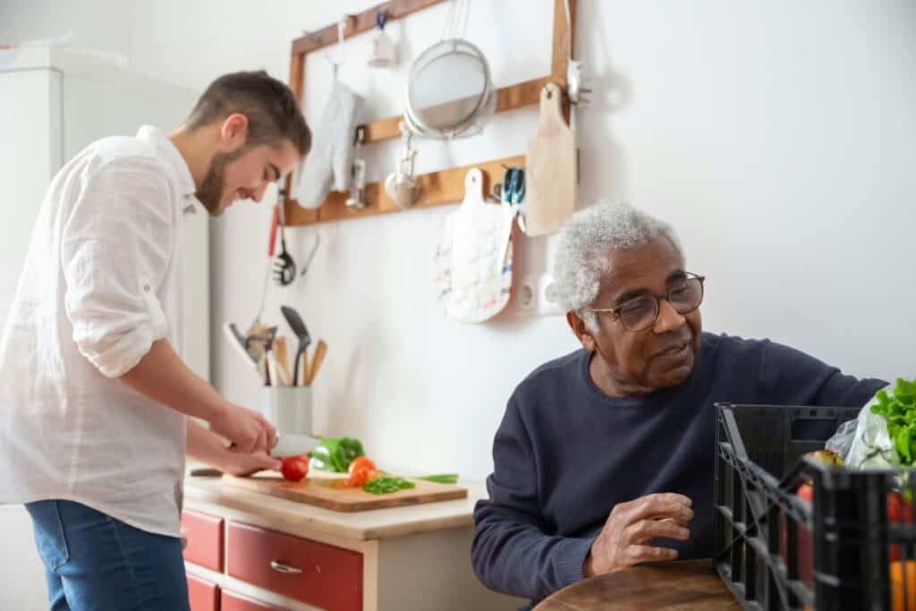 younger man chopping vegetables older man