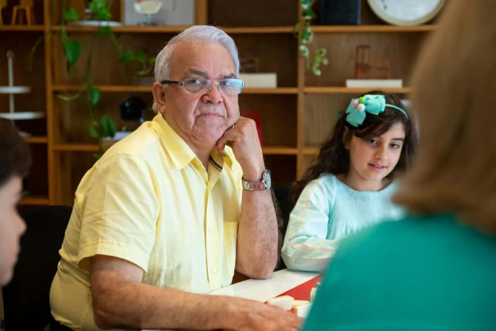 angry grandfather sits at table with kids and another adult