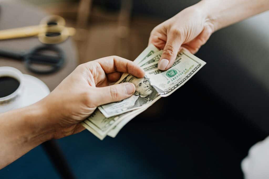 man and woman's hands holding money tug of war