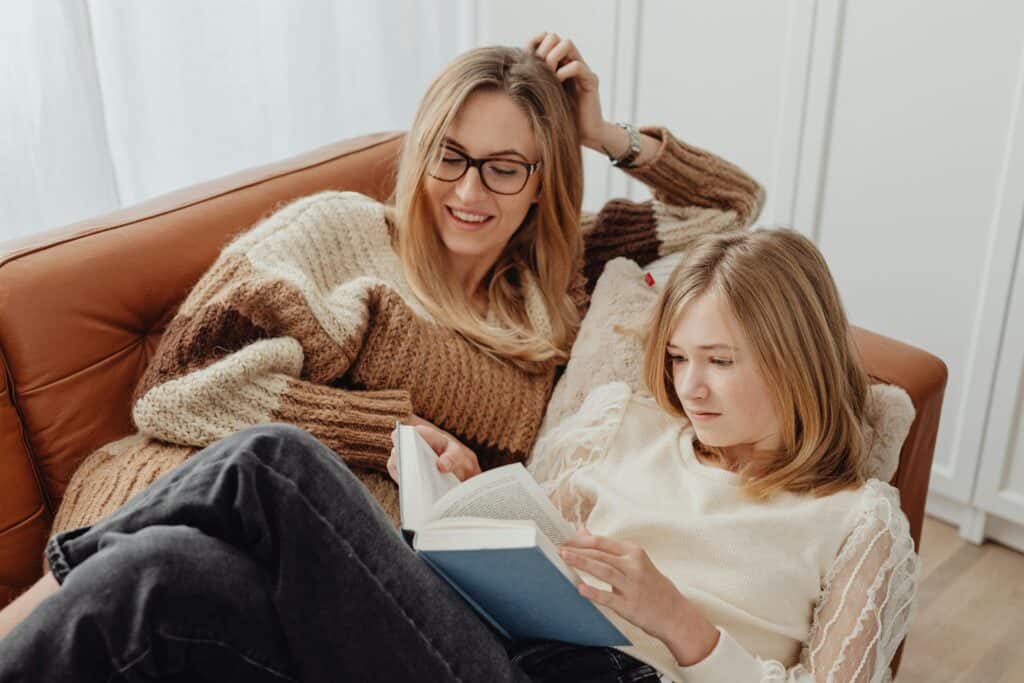 mom and daughter looking at book together on couch