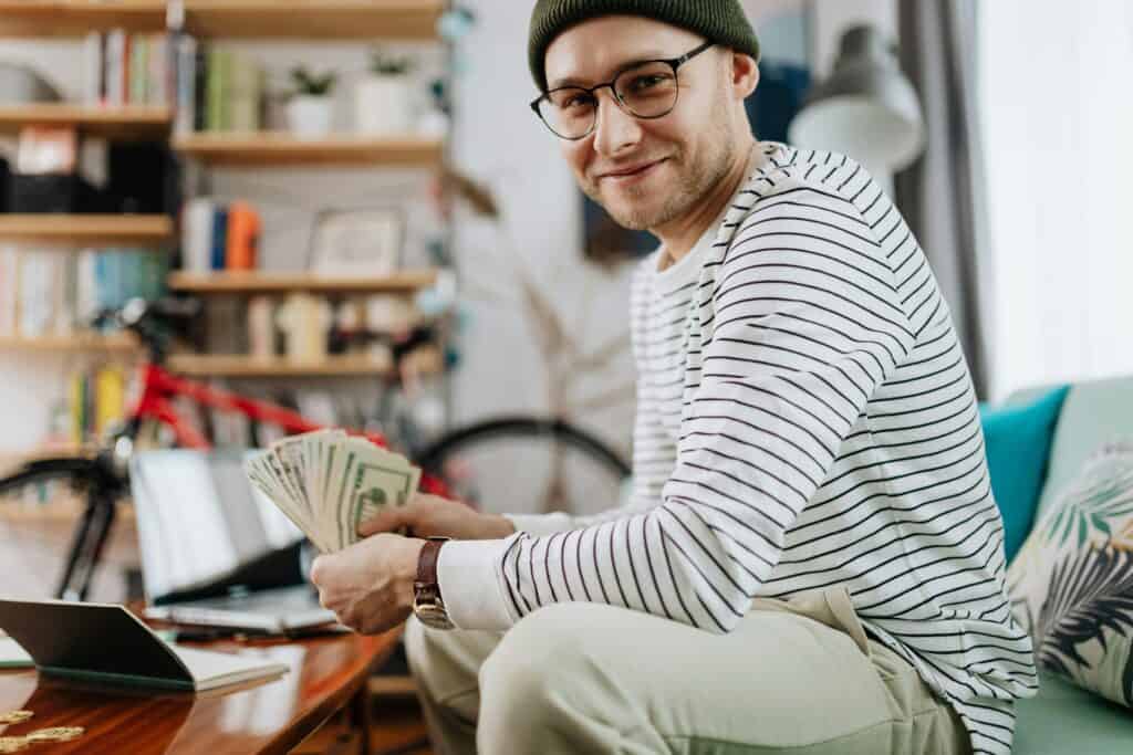 young man holding lots of money usd