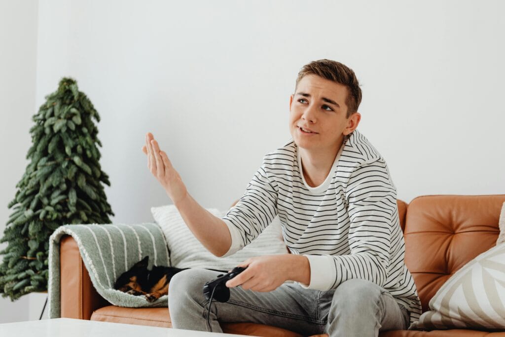 teen boy holding video game control raising hand in annoyance