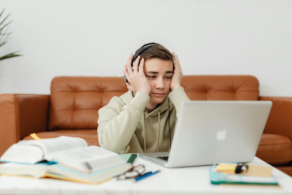 teen looking overwhelmed studying books and computer