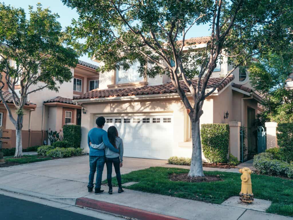 couple arms around each other looking at house