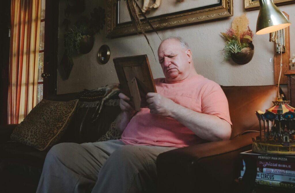 man in living on couch looking at photo