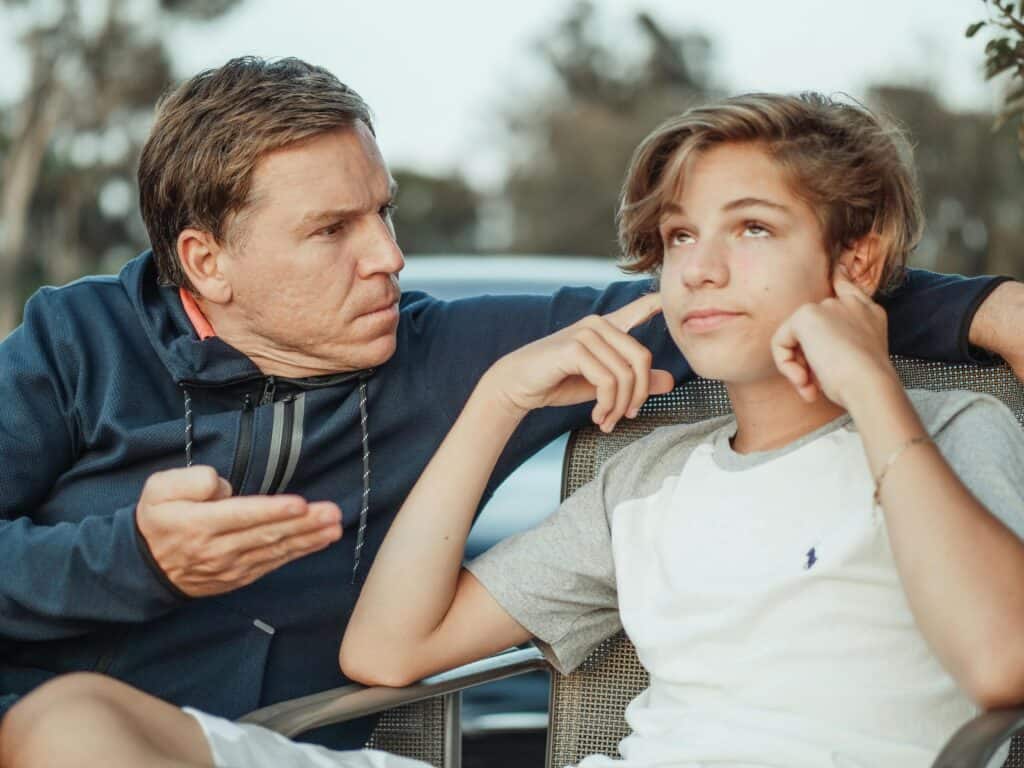 dad talking to teen son plugging ears