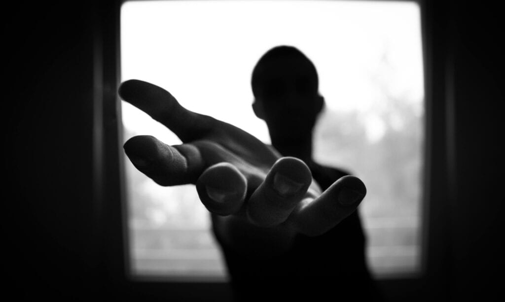 person in shadows hand reaching out