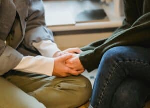 woman holding another woman's hand in comfort