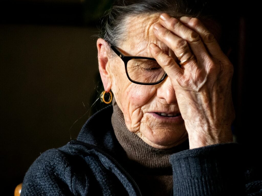 older woman holding hand over face and forehead
