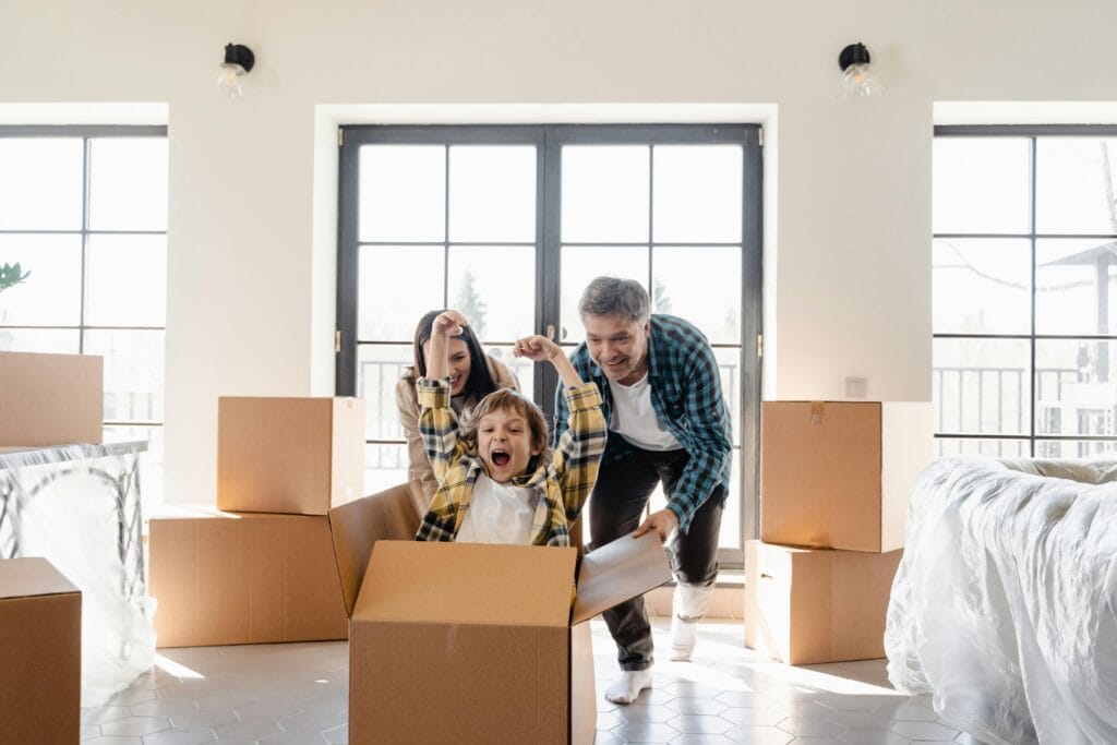 family with moving boxes pushing child in box