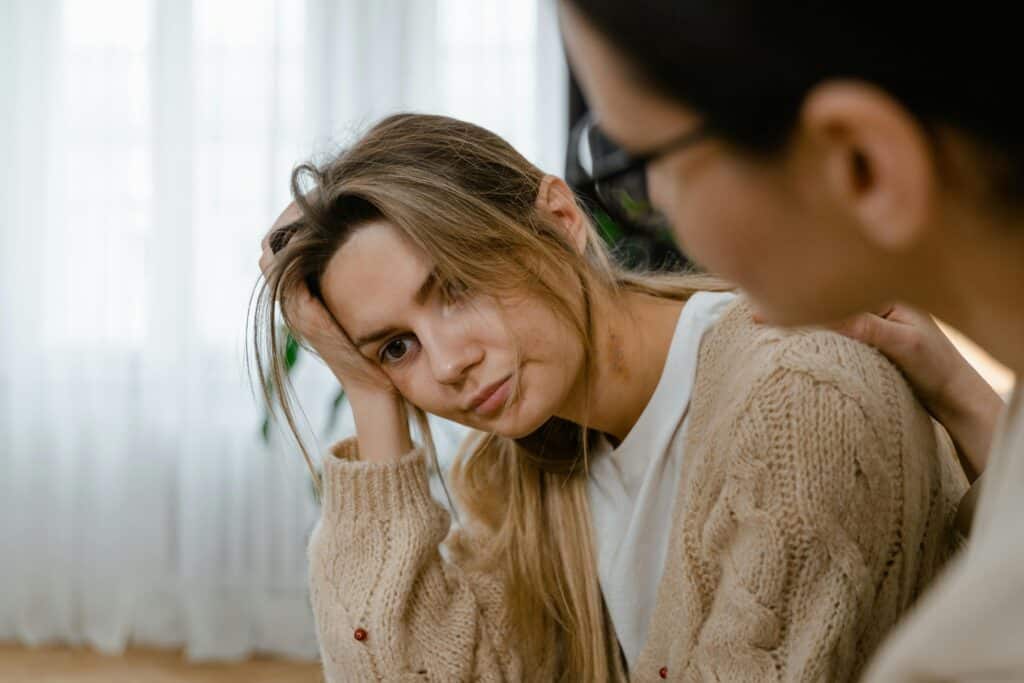 woman with bruises sad being comforted by friend