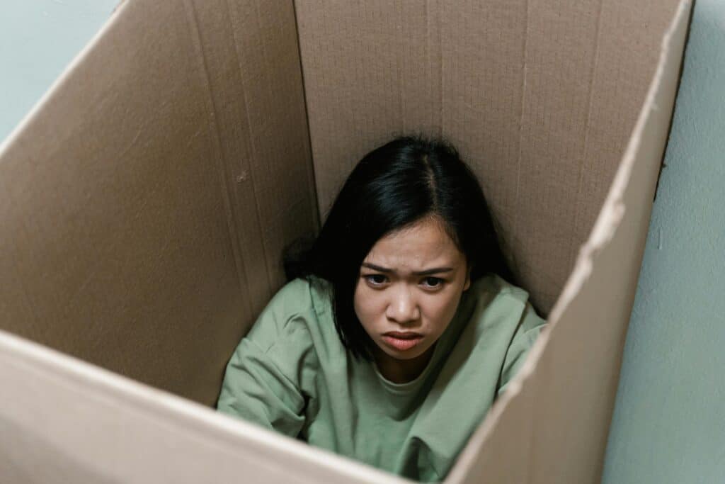 woman in cardboard box unhappy