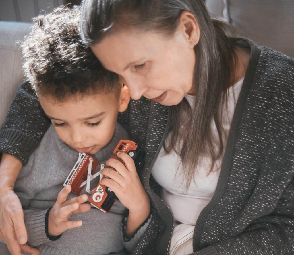 woman and little boy looking down arm around toy truck