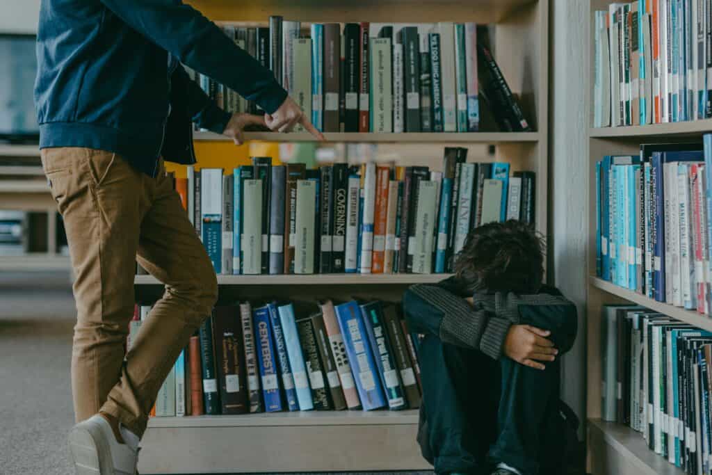 boy standing over and intimidating other boy in library