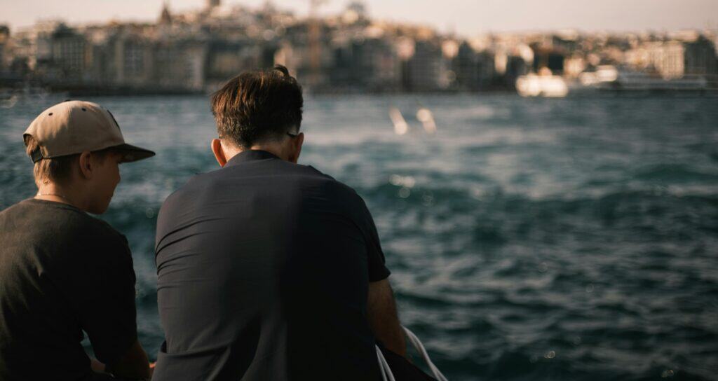dad and son sitting by water talking