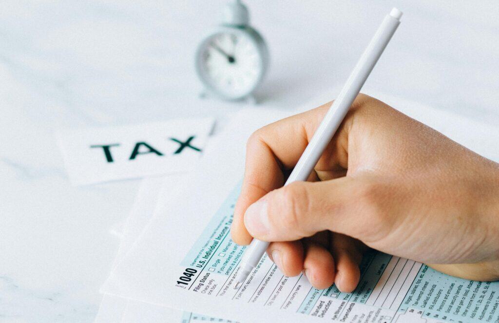 hand filling out tax return 10-40 clock