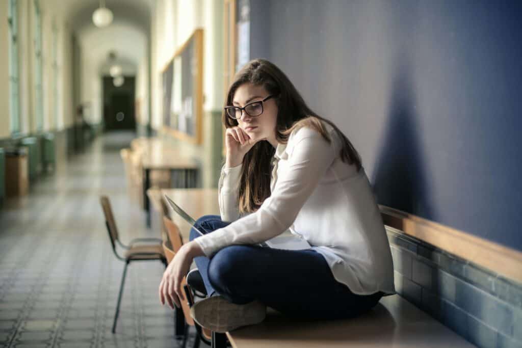 girl sitting on table in hallway discouraged