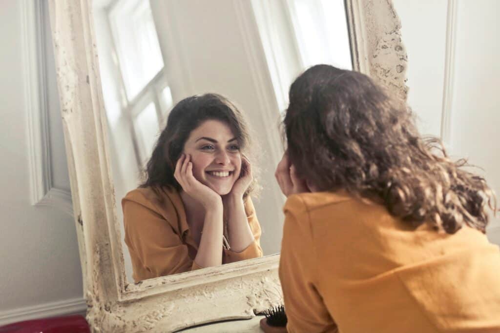 woman smiling at herself in the mirror