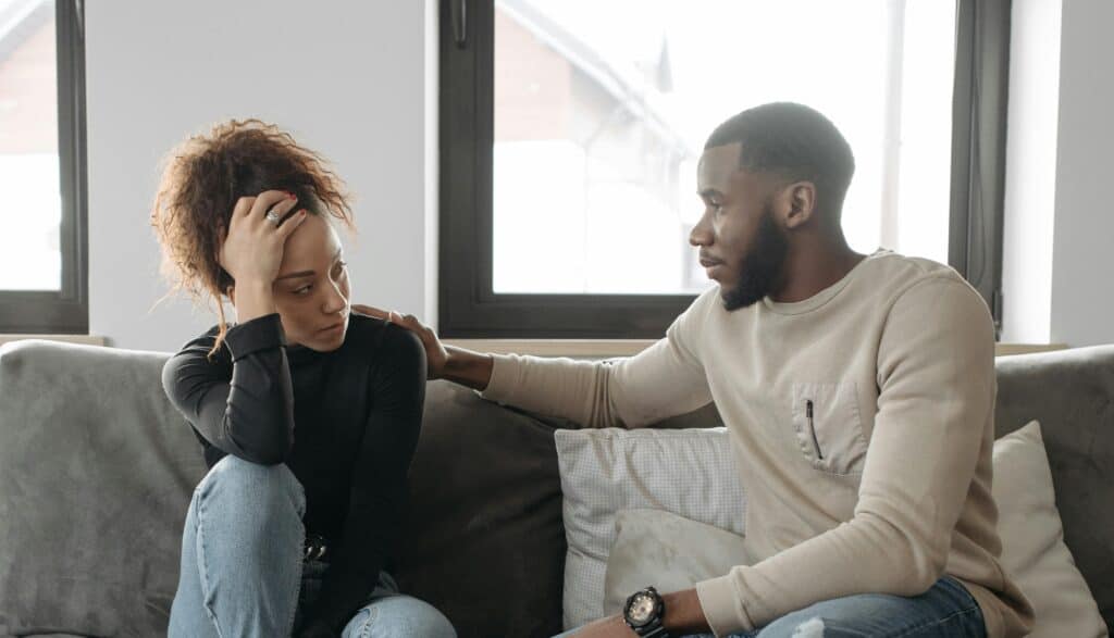 man comforting woman on couch