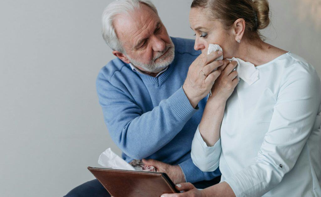 elderly couple crying grieving holding picture frame and tissue