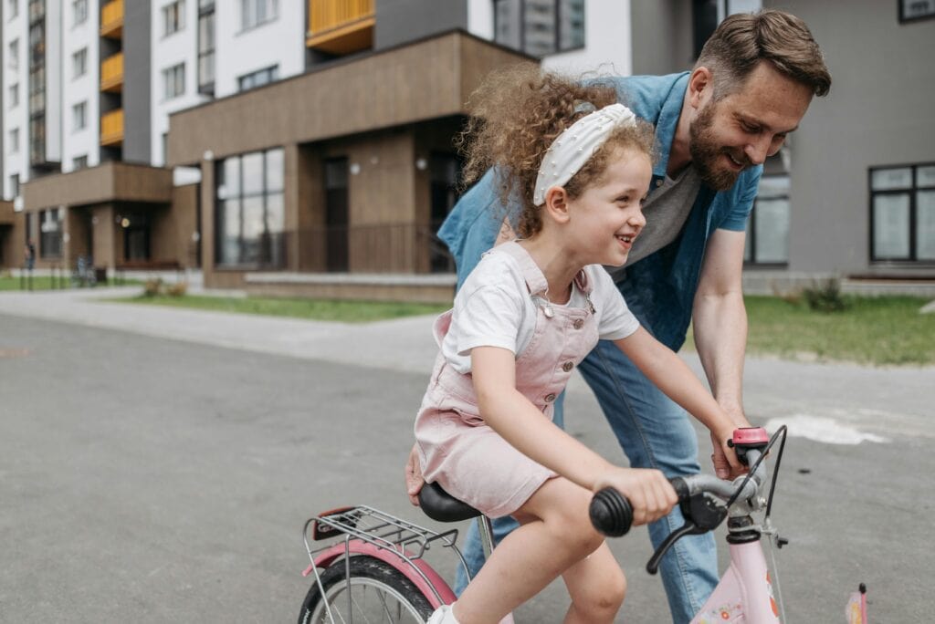 dad teaching daughter to ride bike
