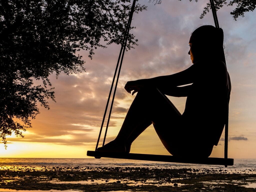 shadow of woman on a swing at sunset