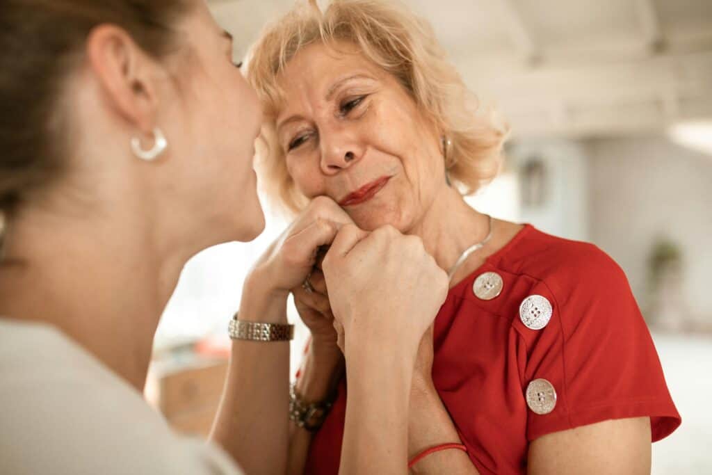 older woman holding younger one's hands love and pride on face