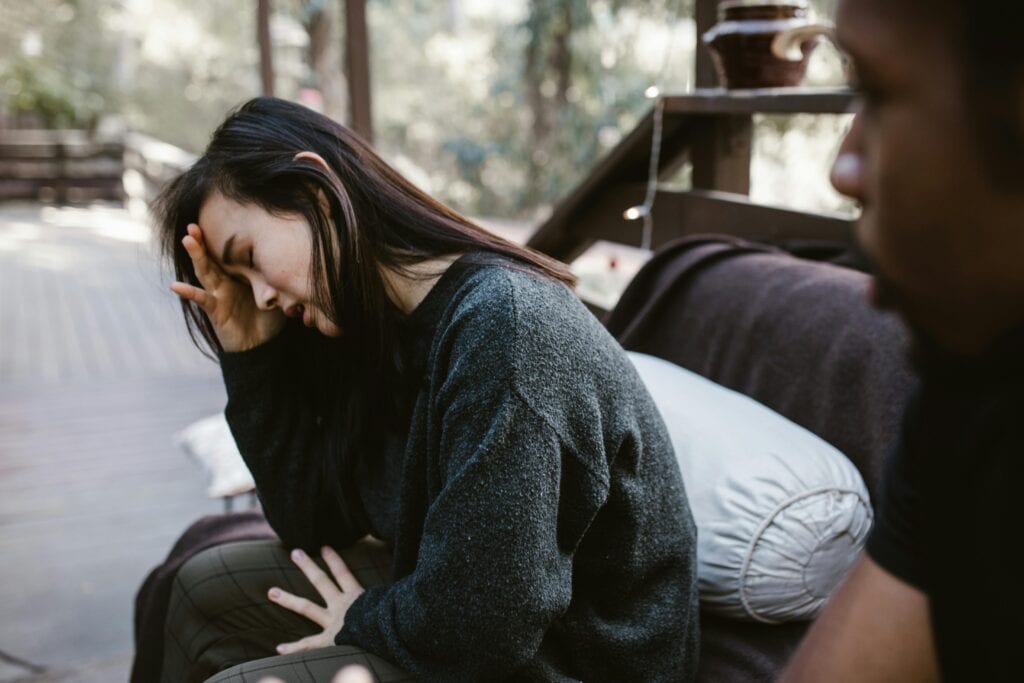young woman crying on bench outside