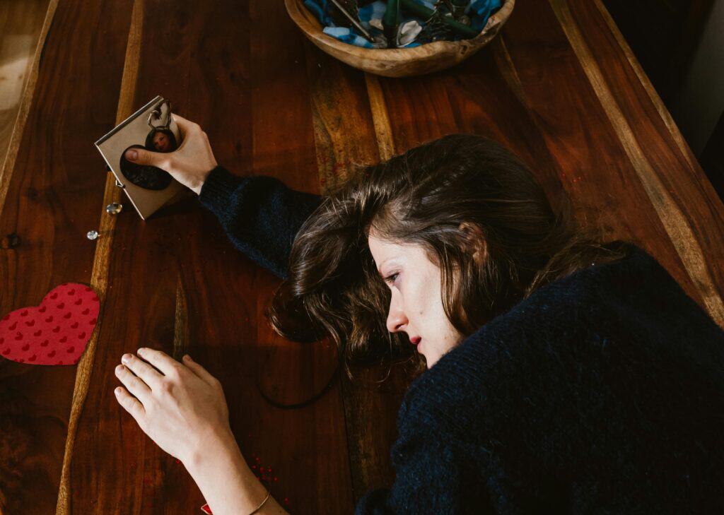 woman crying on table holding heart picture frame