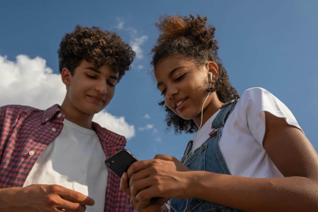 Teen guy and girl listening to music on ipod iphone