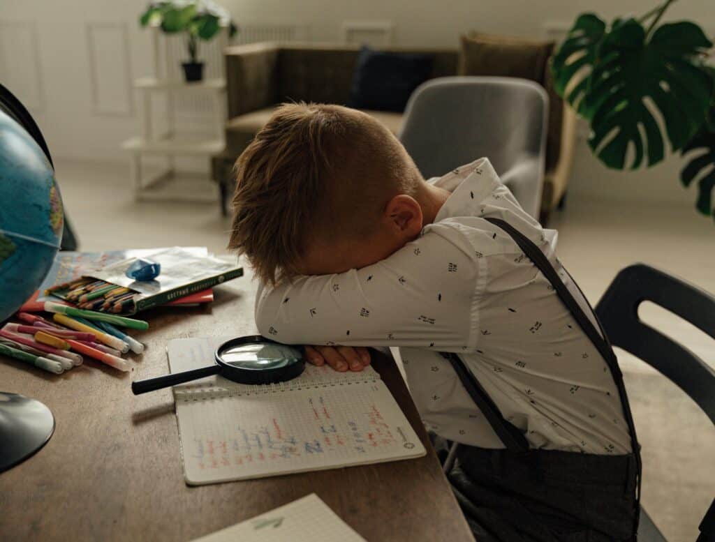 boy leaning over homework tired sad