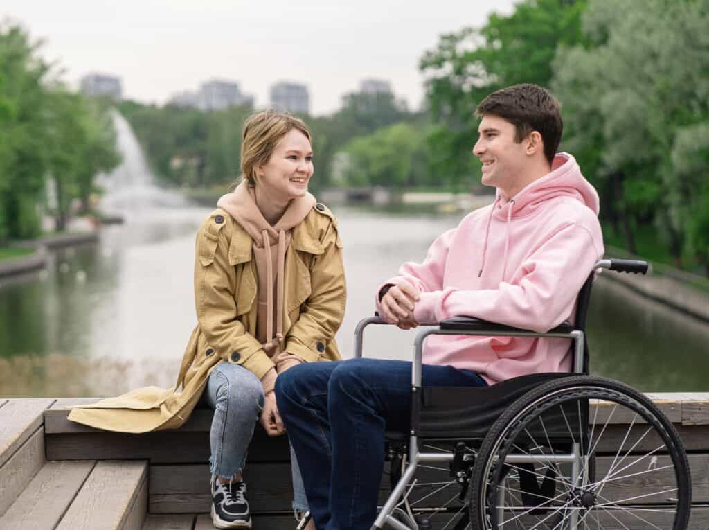 young couple talking in front of water guy in wheelchair