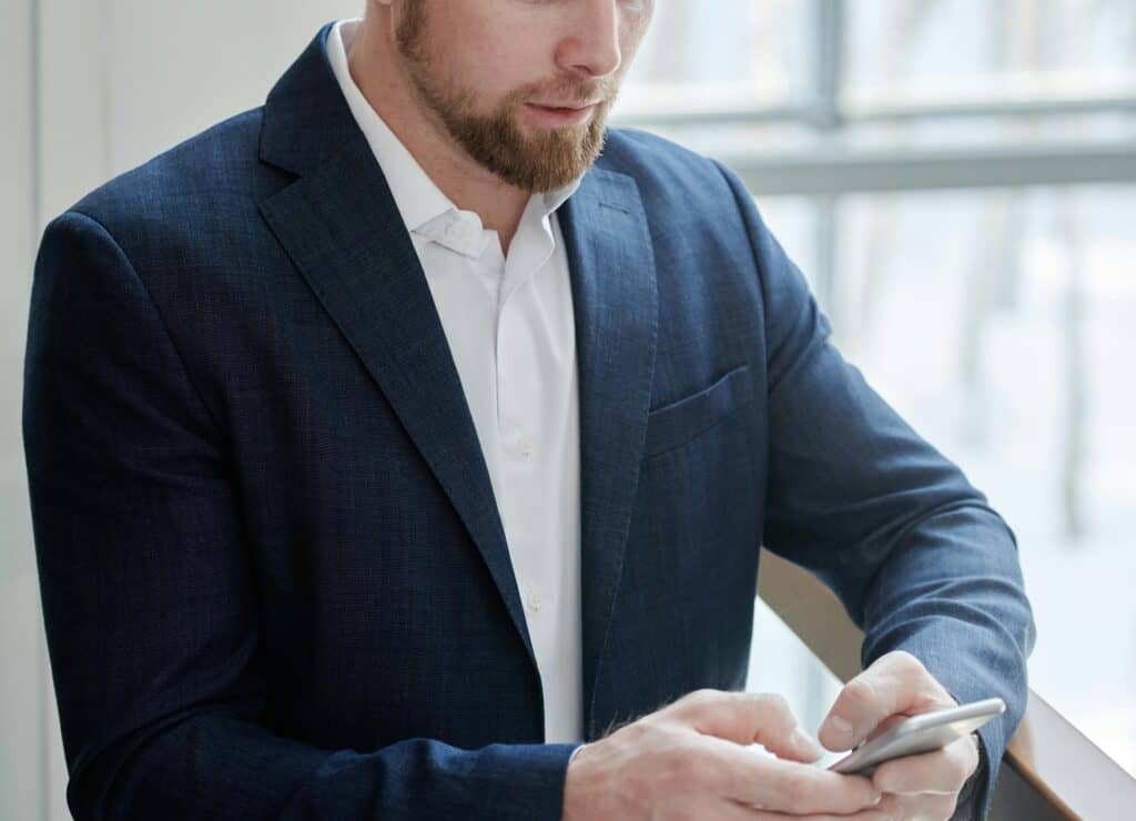 man with beard in suit looking on phone