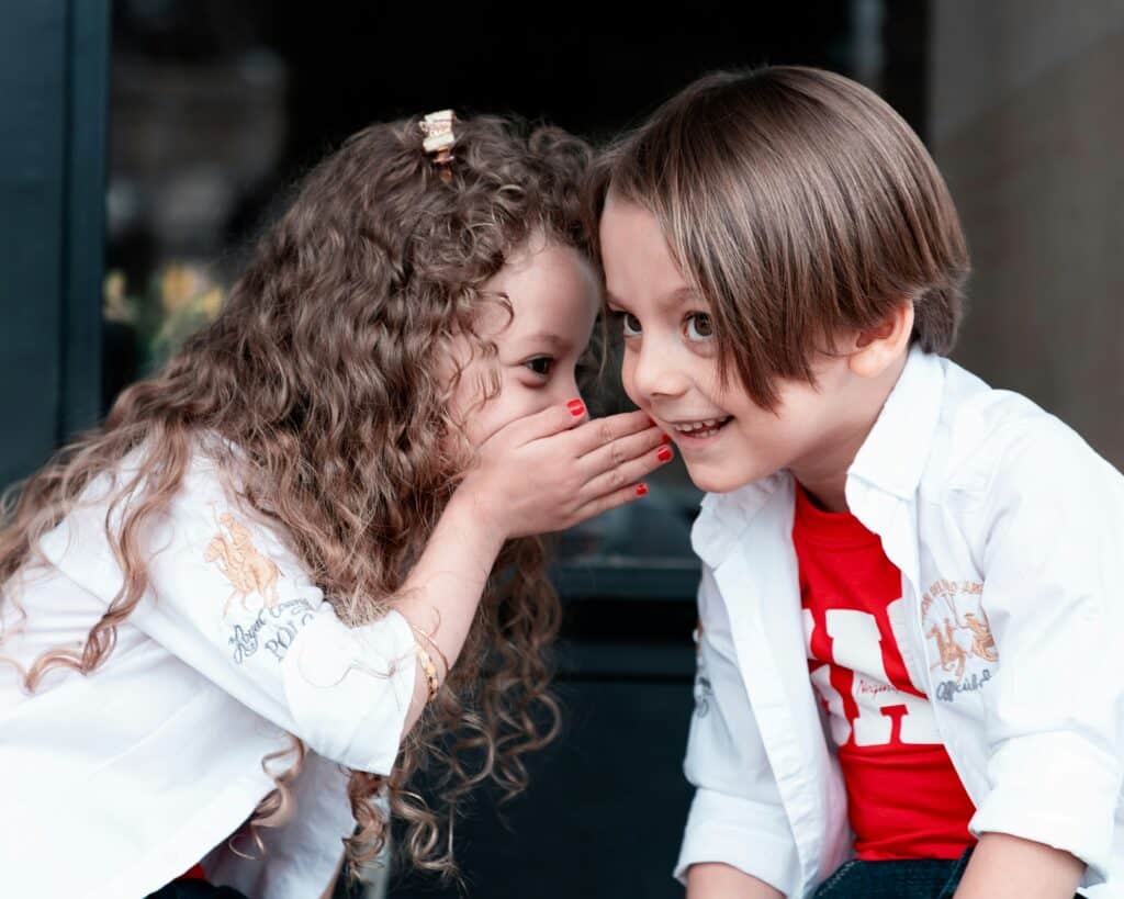 girl whispering to boy